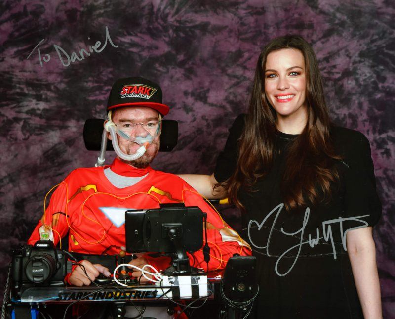 Liv Tyler in black dress standing next to me in my wheelchair with Iron man top and Stark Industries baseball cap