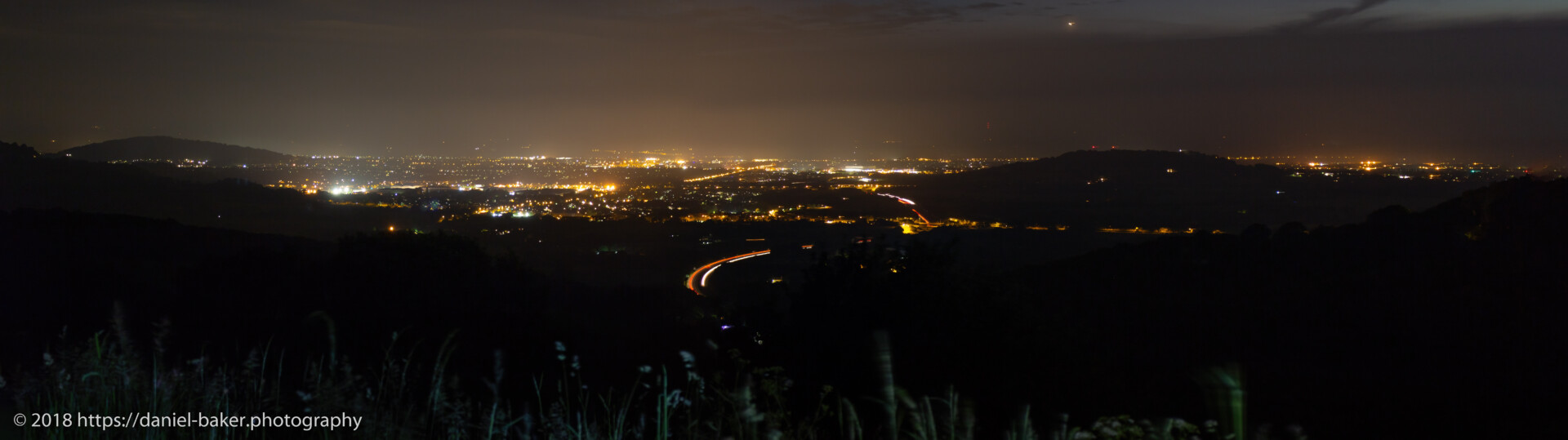 nighttime view looking down on Cheltenham lights and blurred visions of cars speeding along a motorway