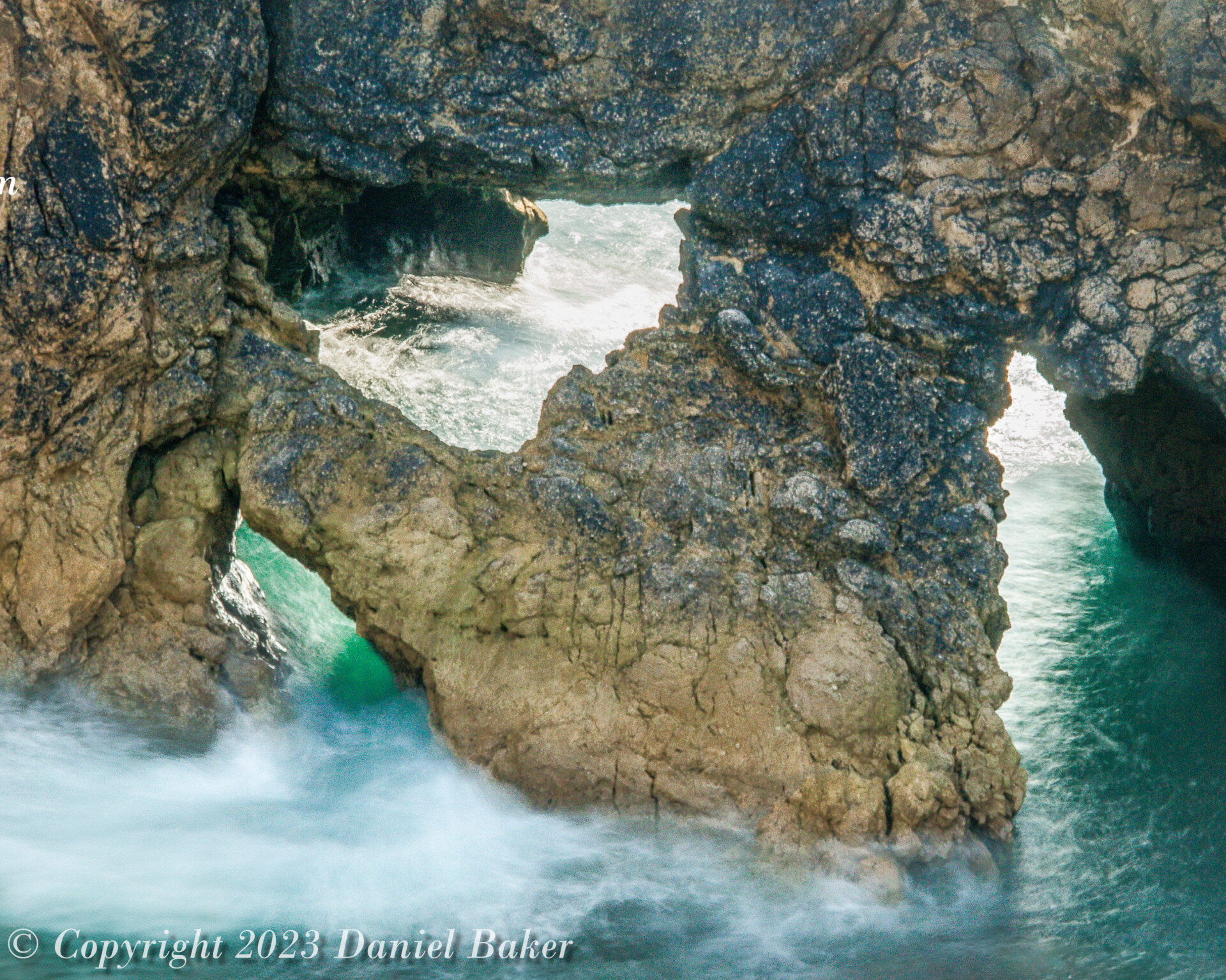 Sea rushing and swirling through a natural stone rock archway